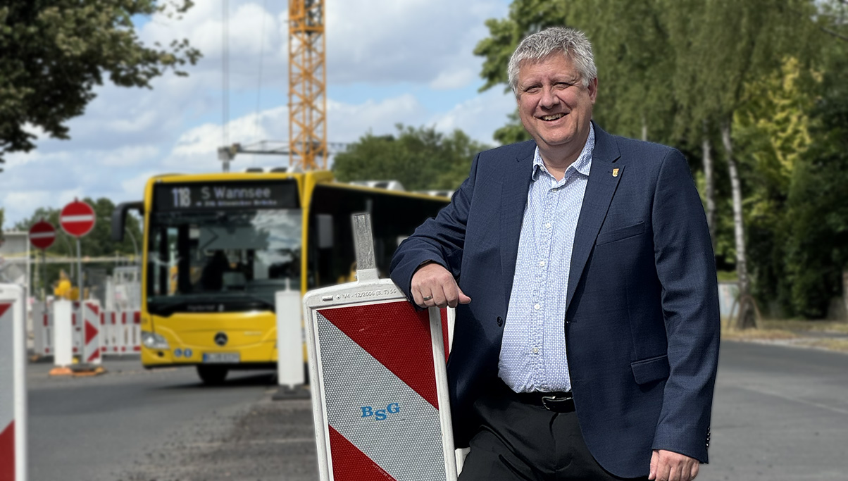 Norbert Buchta steht vor einer Baustelle. Im Hintergrund fährt ein Bus.